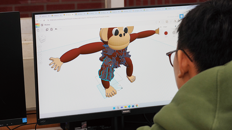 A special needs student designs his monkey on the computer